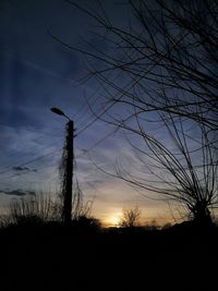 Silhouette bare trees on field against sky at sunset