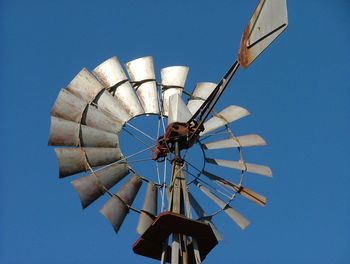 Low angle view of windmill against clear blue sky