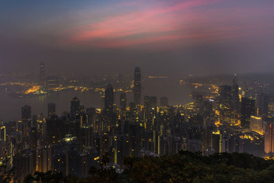 Illuminated buildings in city against sky during sunset