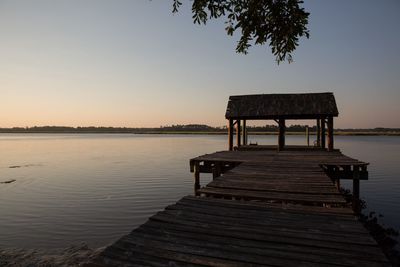 Pier over lake against clear sky at sunset