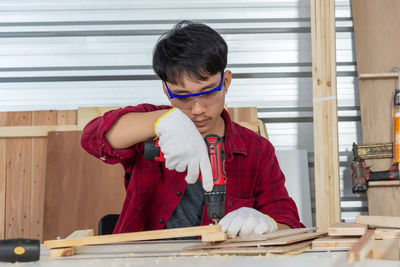 Side view of young man using mobile phone while standing in gym