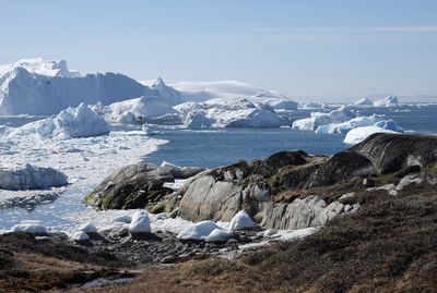 Scenic view of snowcapped mountains by sea against sky