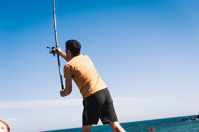 Rear view of man standing by sea against clear sky