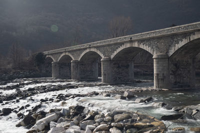 Arch bridge over river against sky during winter