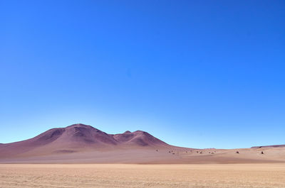 Scenic view of desert against clear blue sky