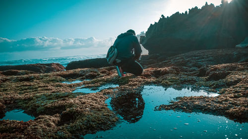 Rear view of man on rock against sky