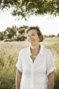 Front view of smiling mature woman standing in grassland