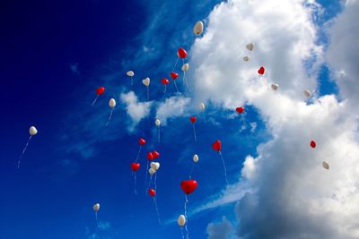 Low angle view of balloons flying against blue sky