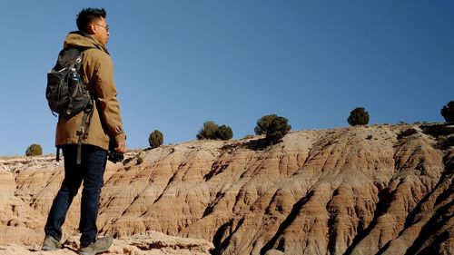 Man standing on rock against sky