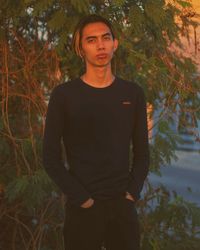 Portrait of young man standing against plants