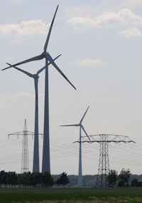 Low angle view of windmills on field against sky