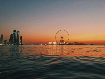 Scenic view of sea against clear sky during sunset with a ferris wheel