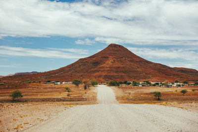 Red desert and gravel roads of damaraland with mountain in background in namibia.