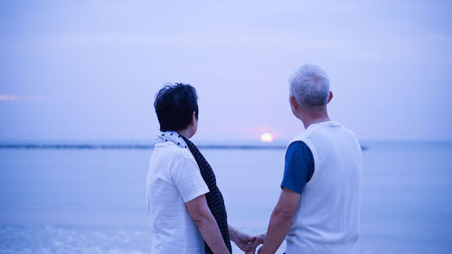 Rear view of couple kissing against sea