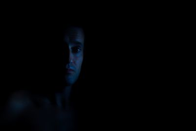 Portrait of young woman against black background