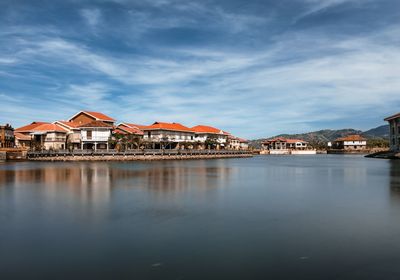 Buildings by lake against sky