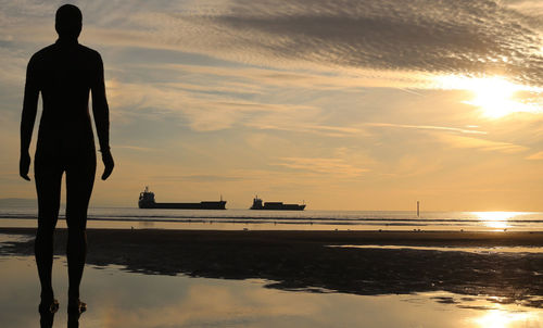 Silhouette man standing on calm beach