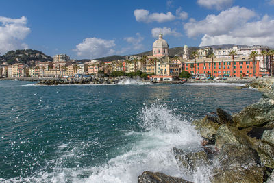 View of buildings by sea against sky in city