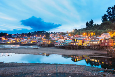 Illuminated buildings by city against sky at dusk