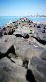 Surface level of rocks on beach against clear sky