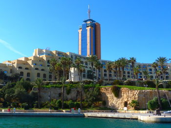 View of swimming pool by building against clear blue sky