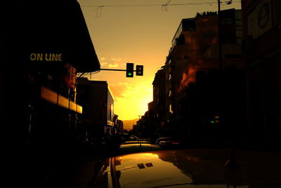 City street amidst buildings against sky during sunset