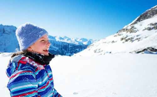 Portrait of woman standing on snowcapped mountain against sky