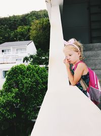 Full length of cute girl amidst plants against building