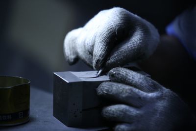 Cropped hands wearing gloves holding box on table