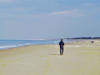 Rear view of man on beach against sky