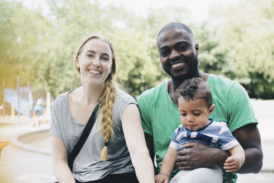 Portrait of smiling parents sitting with son at park