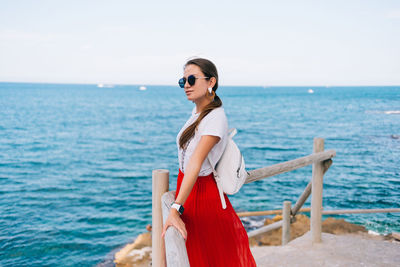 Woman standing by sea against sky