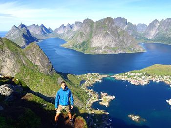 High angle view of man standing on mountain against sea at moskenesoya