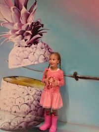 Full length of a smiling girl standing against pink background