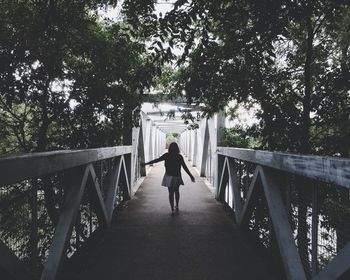 Rear view of woman standing on footbridge