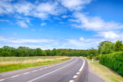 Road amidst field against sky