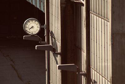 Close-up of clock against sunny wall in building