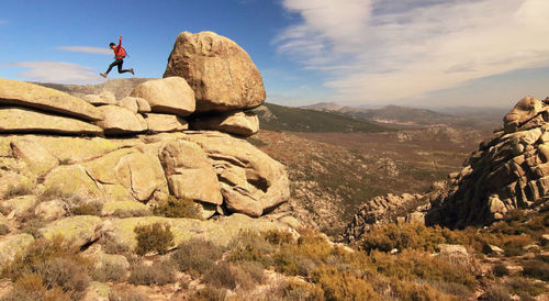 Low angle view of man jumping on cliff against sky