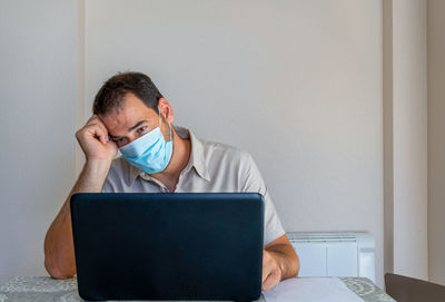 Frustrated man wearing flu mask sitting at office