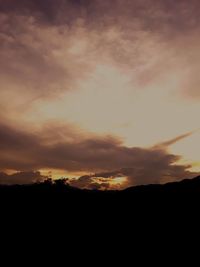 Silhouette landscape against dramatic sky during sunset