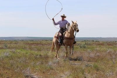 Man riding horse on field against sky