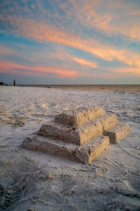 Scenic view of sand castle on white sand beach against sky during sunset