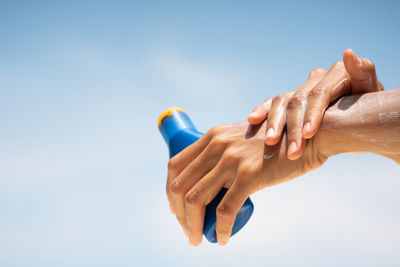 Close-up of woman hand against blue sky