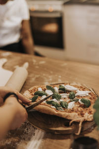 High angle view of person cutting pizza