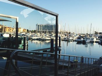 Boats moored at harbor against clear sky