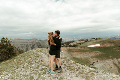 Newly engaged white couple kiss on a mountain top in wyoming