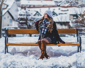 Woman sitting on bench in snow