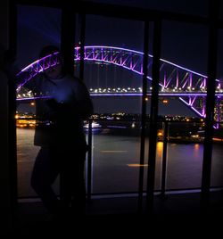 Rear view of silhouette man standing on bridge at night