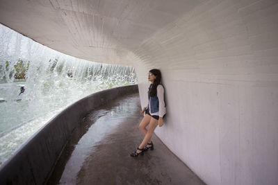 Woman leaning on wall against dam