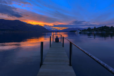 Pier over lake against sky during sunset